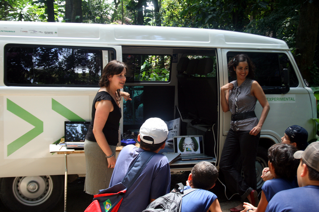 Rachel and Silvia showing children a projection of a data visualisation inside the EME van in the Mata Atlantica forest, Brazil