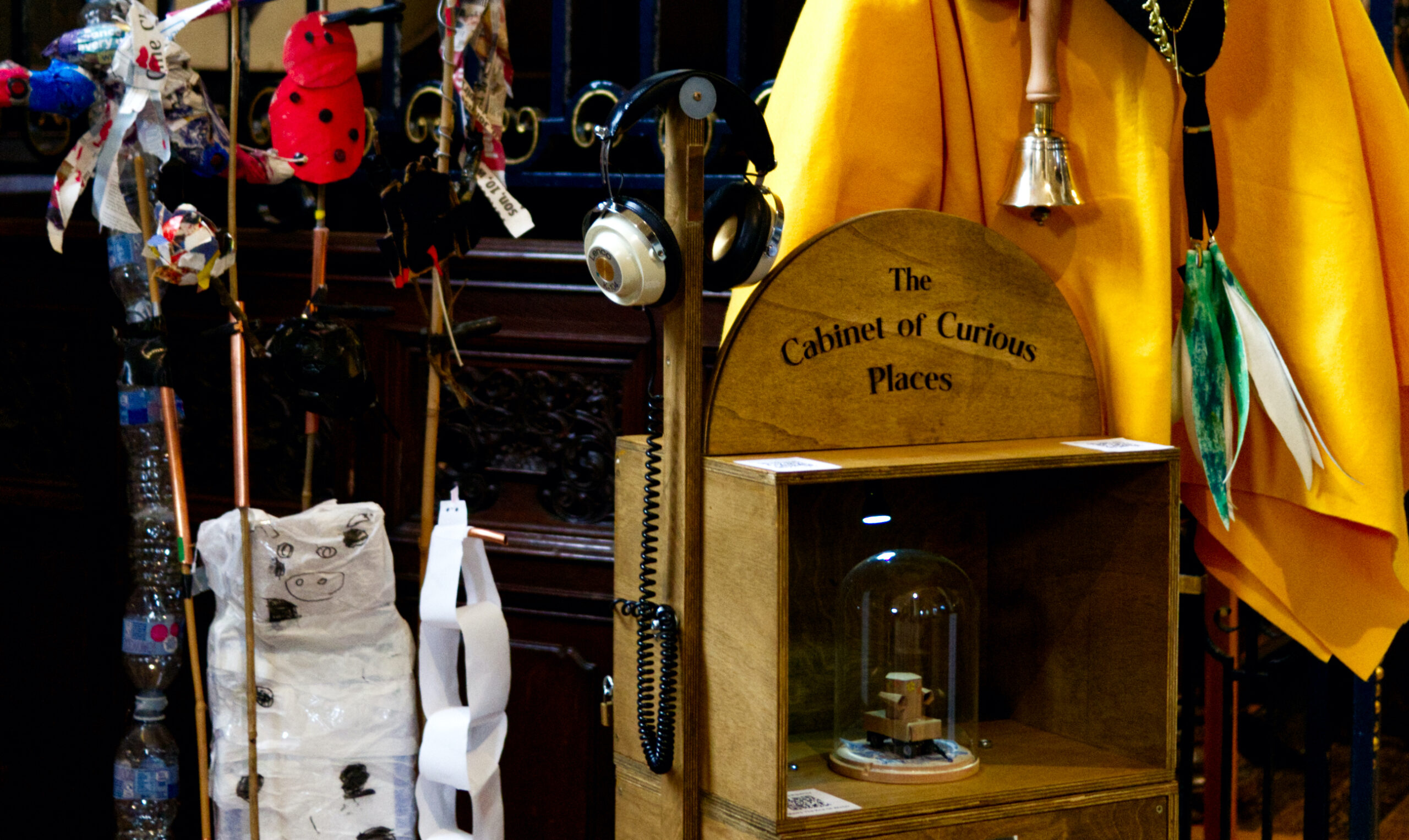 Woorden Cabinet of Curious places, bell, yellow costume and plants and creatures made from rubbish