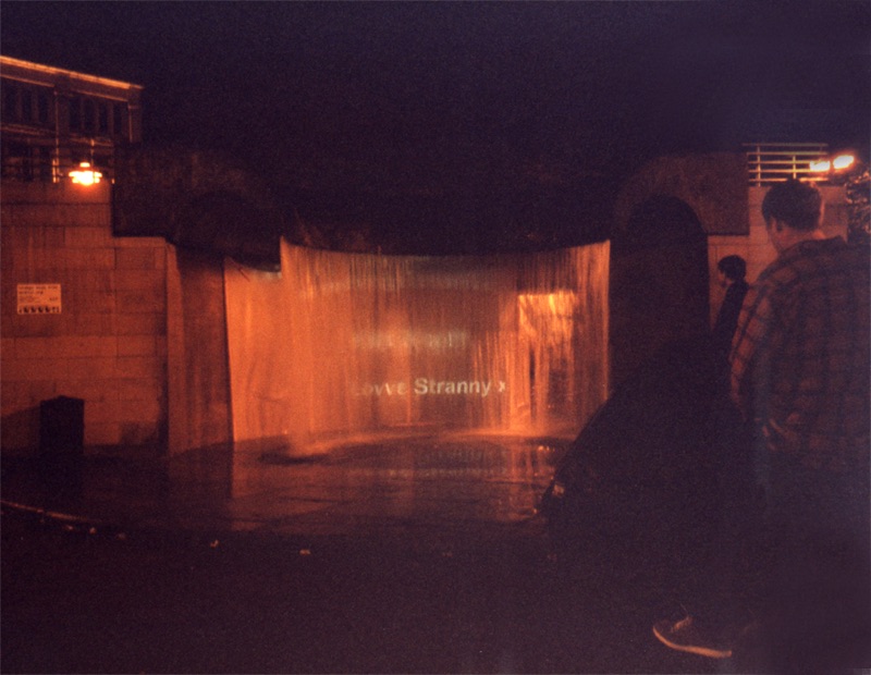 water with text projected into it, a man standing by the tent, in the dark